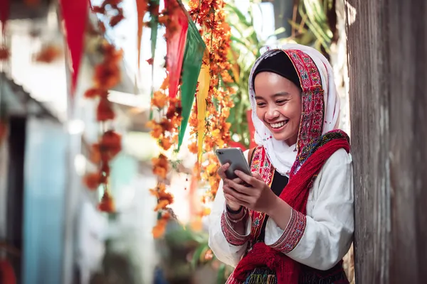 A player using their smartphone during a festive local event, representing DEAWUN’s fully mobile-friendly casino.